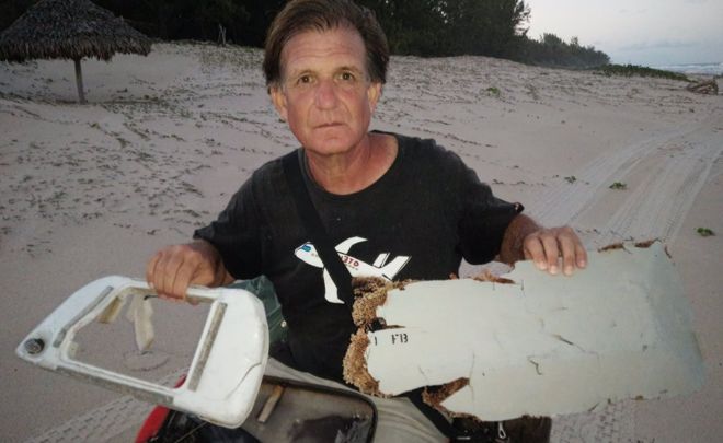 Ông Blaine Gibson chụp cùng các mảnh vỡ nghi của máy bay MH370 mới tìm thấy ở Madagascar. (Ảnh: BBC)