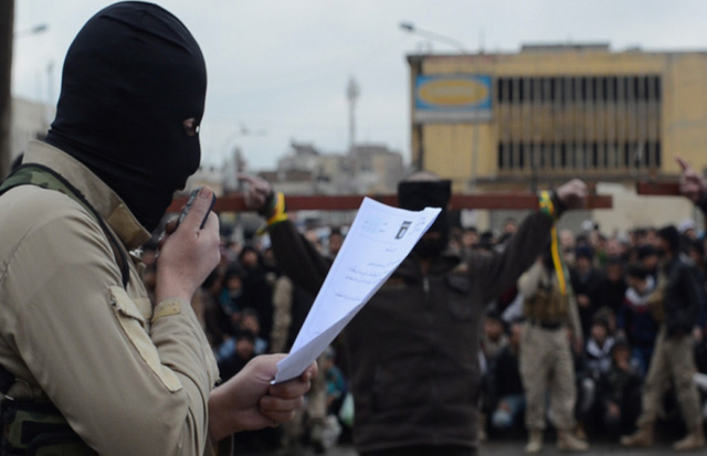 Một chiến binh IS đọc to cáo trạng tòa án Sharia ban hành trước khi hành quyết công khai nạn nhân (Ảnh: Iraqi News)