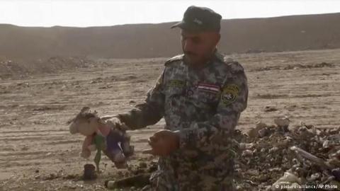 Chiến binh Iraq tìm thấy con thú bông ở hố chôn tập thể.
