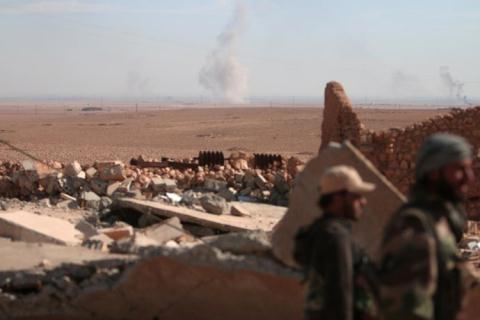 Khói bốc lên ở phía xa xa khi các thành viên SDF lục soát hiện trường đổ nát ở bắc thành phố Raqqa.